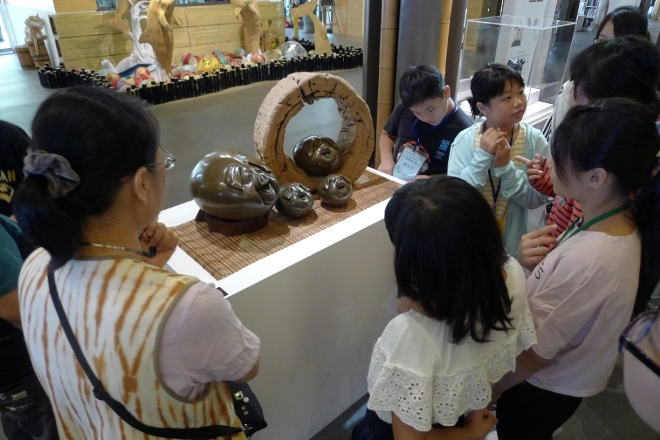 由導覽員介紹地方工藝館「洄游-竹木石創作聯展」及相關創作，讓學童大開眼界。(記者張光雄翻攝)