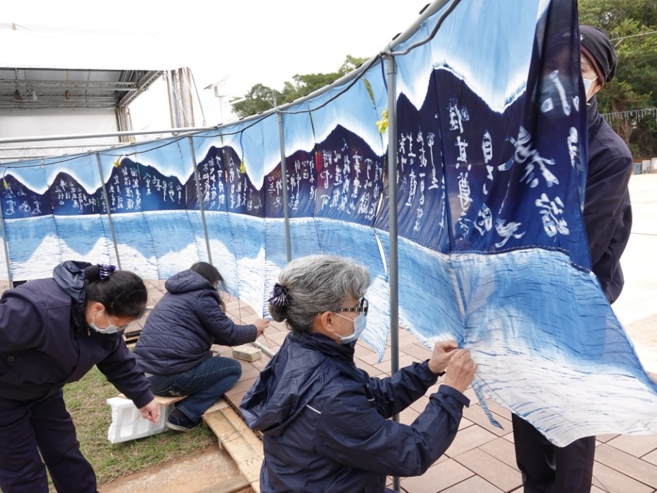 燈會前，慈濟志工用手工將藍染方巾一針一針密密縫，從早到傍晚方告完成。(記者曾憲群翻攝)