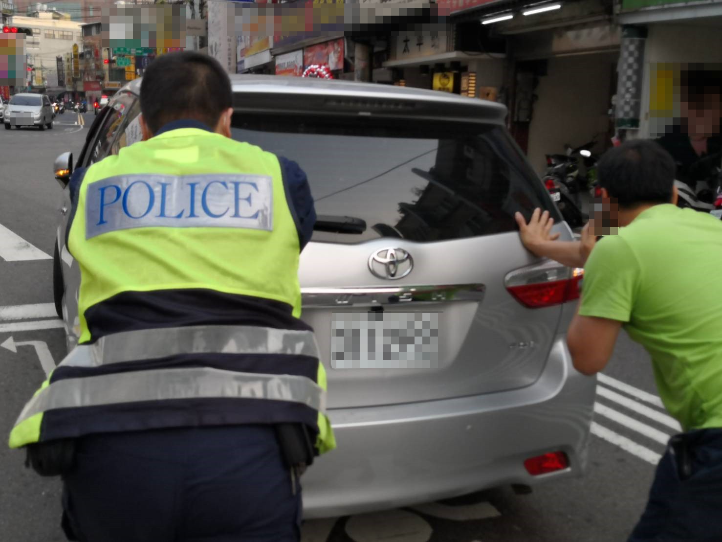 婦人控制方向盤，員警與熱心民眾將車推路旁。(記者劉明福翻攝)