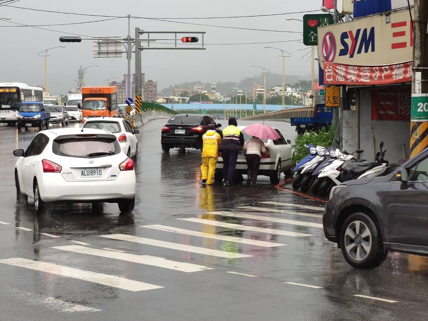 大雨中車輛拋錨 暖警徒手推車救援。(記者白信東翻攝)