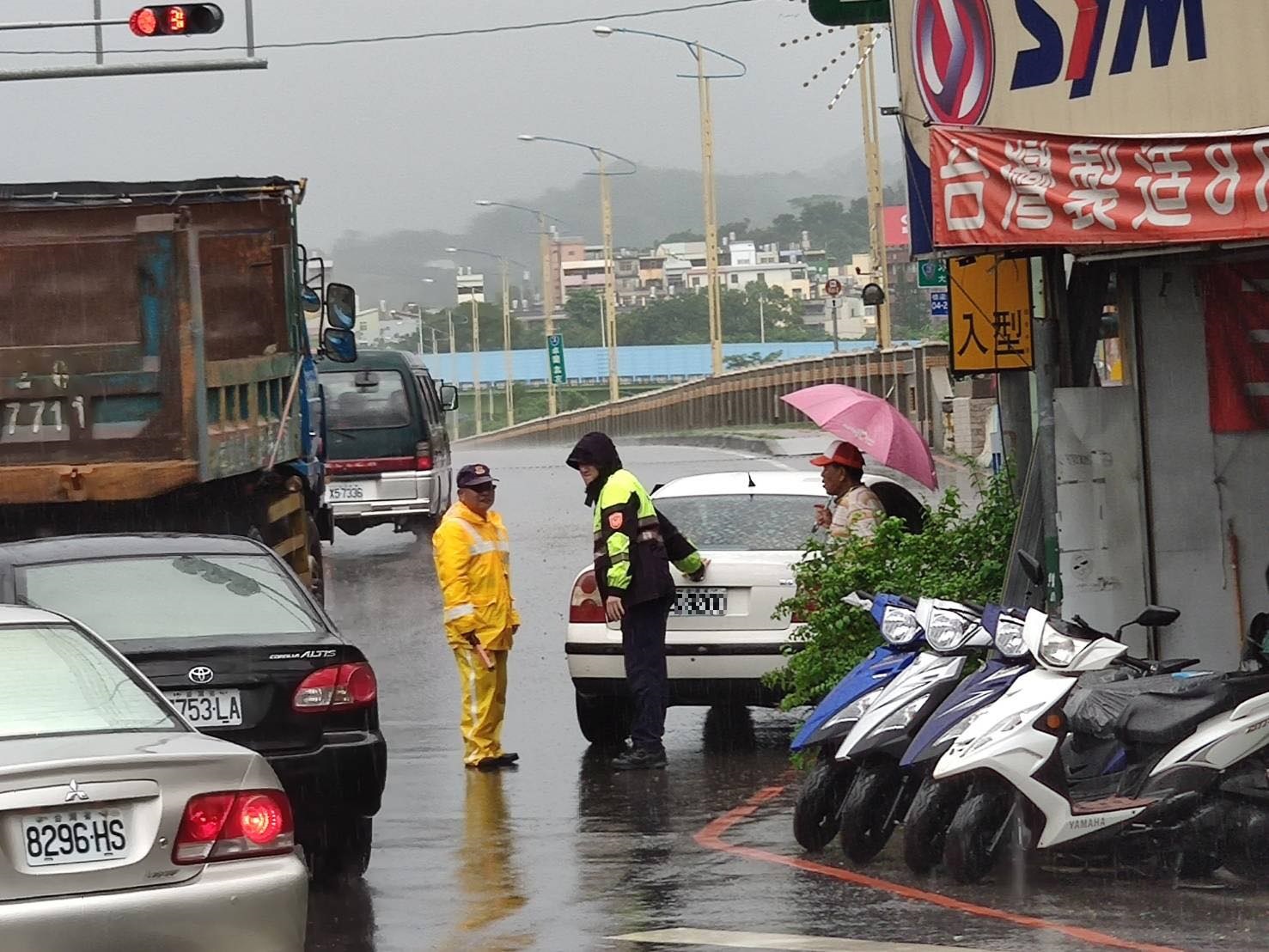 大雨中車輛拋錨 暖警徒手推車救援。(記者白信東翻攝)